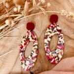 Boucles d'oreille longue de forme ovale ajouré en son centre avec un clou d'oreille carré rouge grenadine