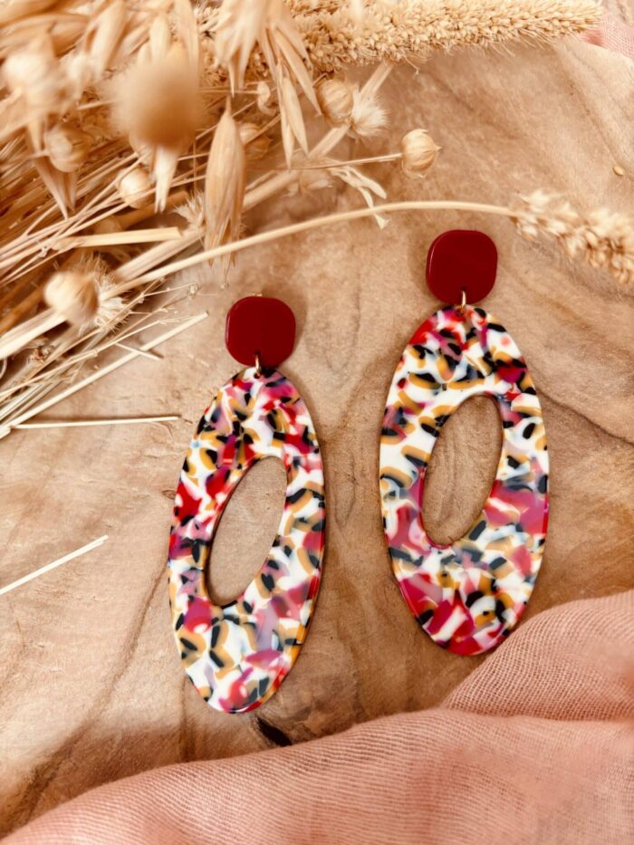 Boucles d'oreille longue de forme ovale ajouré en son centre avec un clou d'oreille carré rouge grenadine