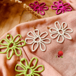 Boucles d'oreilles XXL en forme de fleur en acier inoxydable. Les fleurs sont colorées car recouvertes de raphia