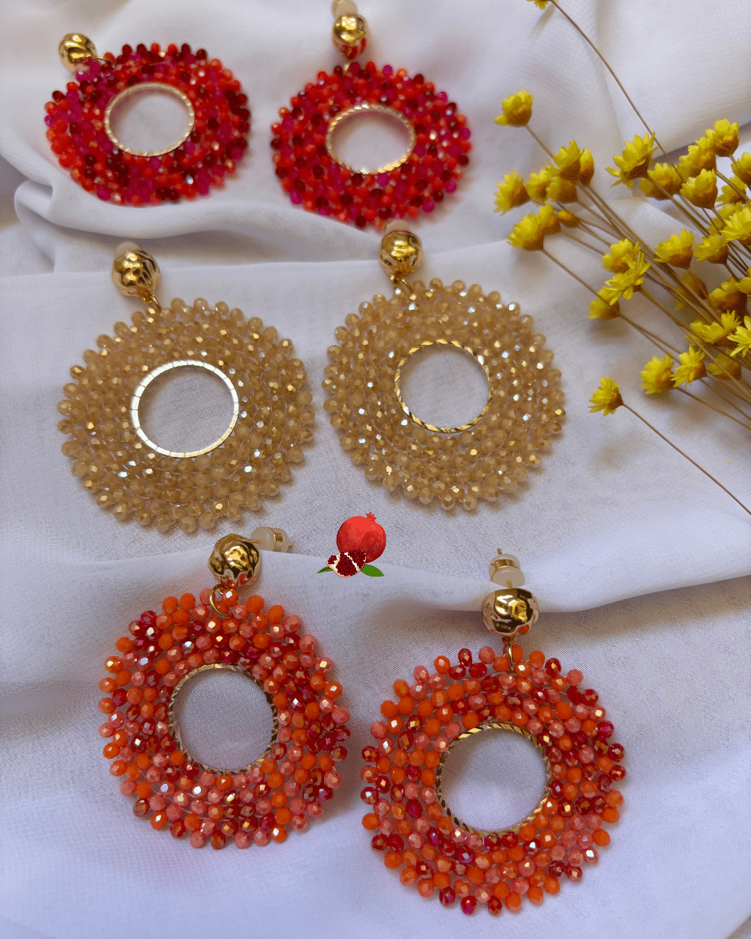 Solyn Clou d’oreille en plaqué or Pendentif tissé à la main avec perles en crystal de verre (diamètre 5 cm) 3 coloris disponibles : ambre, orange, rose/rosse fuschia Longueur : 6 cm