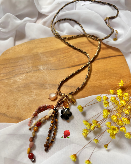 Sautoir bohème en fil tressé avec pendentifs divers en résine, acier inoxydable et breloques en pierre naturelle Pierre : tourmaline noire, rhodochrosite et oeil de tigre Longueur chaine : 88cm (+ 5cm chainette d'extension)